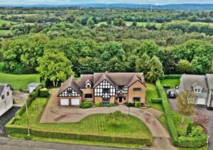 The front exterior of 229 Mountsandel Road. This is a birds eye view of the property which overlooks the woodland to the rear. Well-maintained gardens are found to the front, side and rear of the property with hedging separating the property from the neighbours.
