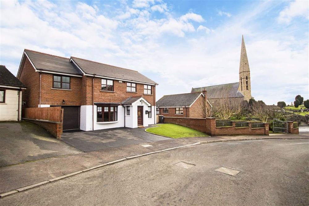 The exterior of Church Glen, a home for sale in Lisburn. This is a detached home with an integral garage. A large tarmac area is seen to the front of the property offering ample off-street parking space.