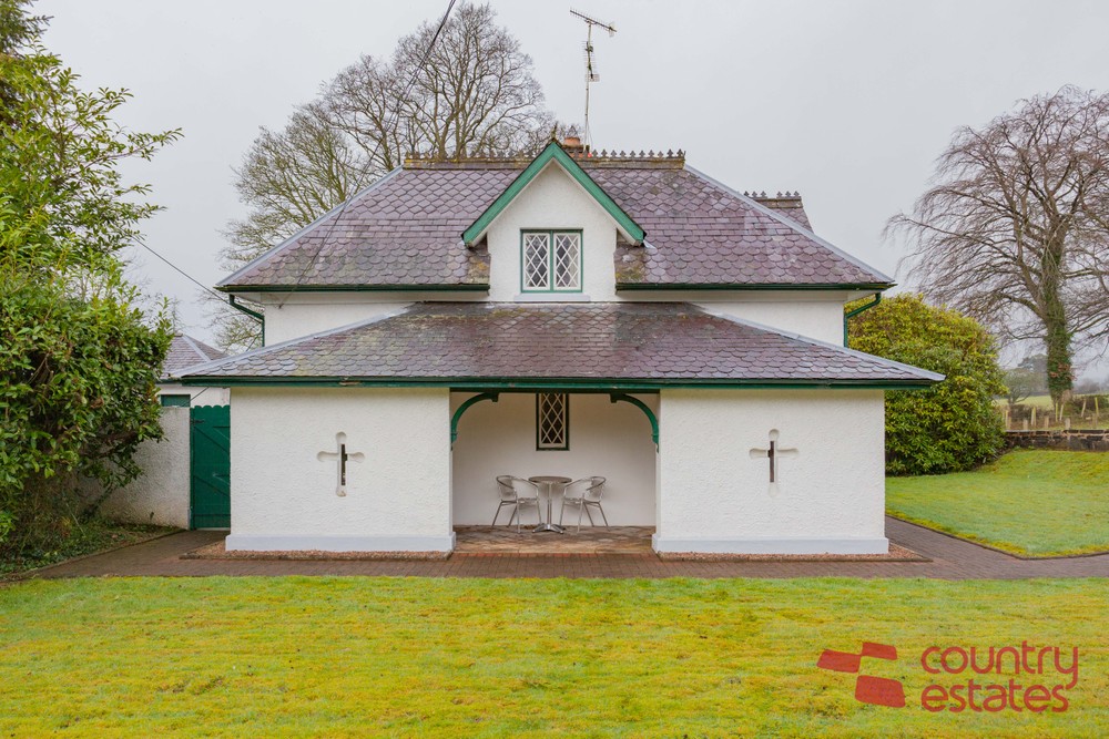 The exterior of The Old Lodge. Beautifully maintained gardens can be seen to the front and side of the property. Image used in the 189-year-old Ballymena Gate Lodge on the market blog post.