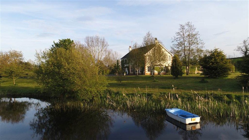 The exterior of 116 Old Ballynahinch Road, a home for sale in Lisburn. This image depicts the extensive grounds that surrounds the property along with a private lake.