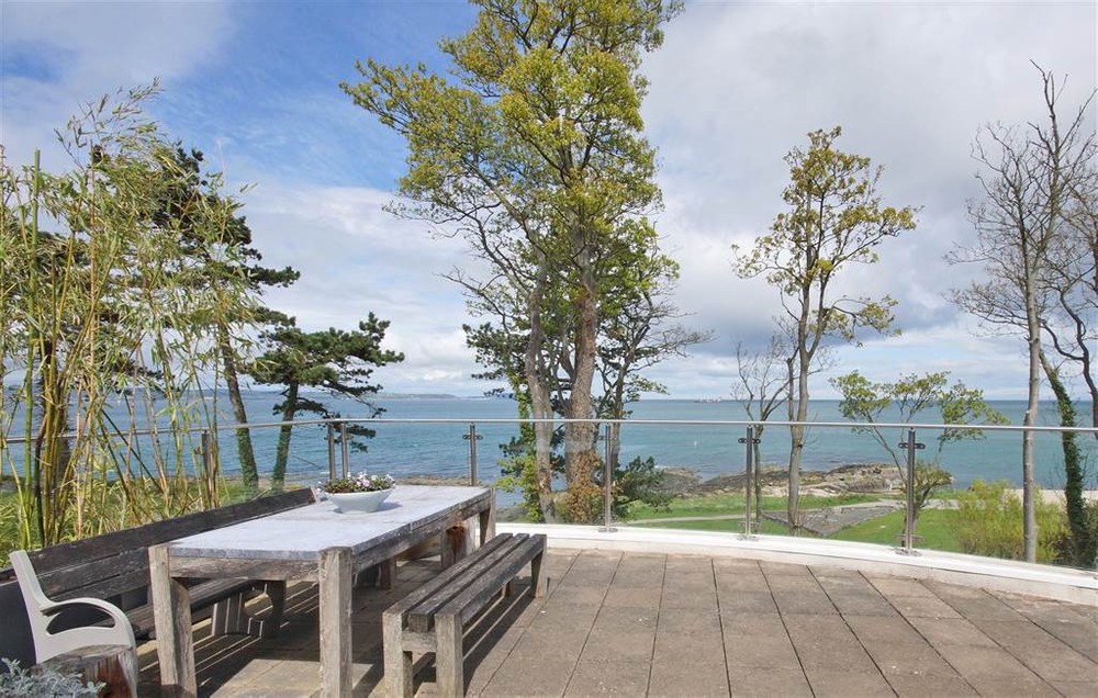 The sea views from 5a Brompton Road. This image shows the outdoor dining area overlooking the sea vista. Featured image for Houses for sale in Northern Ireland with sea views blog post.