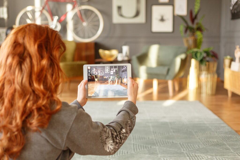 A woman filming a lounge interior. Image used in the Virtual property viewings: How to create a video tour of your property blog post.