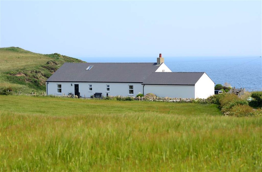The exterior of 31b Sheepland Road, a 2 bedroom house for sale in Co. Down. The Irish Sea can be seen in the background.