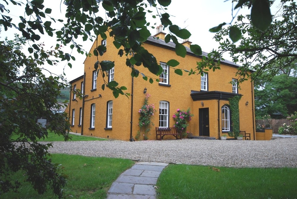 The exterior of Aghanloo House, a period home for sale in Limavady. The exterior is an orange colour which reflects the original colour of the exterior when it was built almost 300 years ago.