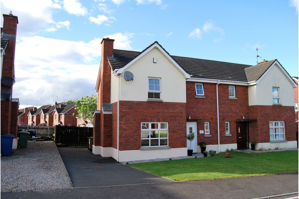 The exterior of 69 Moyraverty Meadows. This is a semi-detached property for sale in Craigavon. Neat lawns can be seen to the front of the property along with a path that leads to the front door. A tarmac driveway runs along the left side of the property.